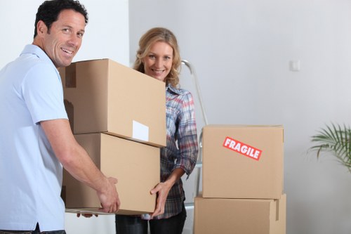 Local movers handling a sofa and bed frame in a tight stairwell